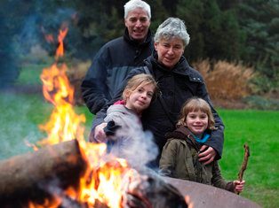Een oudere man en vrouw met twee kinderen verwarmen zich bij een brandende vuurkorf, winterse opendeurdag in Arboretum Kalmthout.