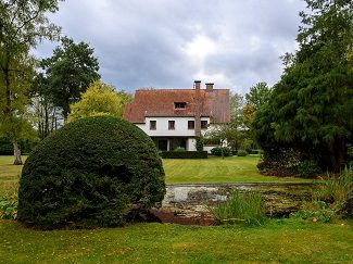 Zicht op een witte villa met grote tuin en vijver in de uitbreiding van Arboretum Kalmthout.
